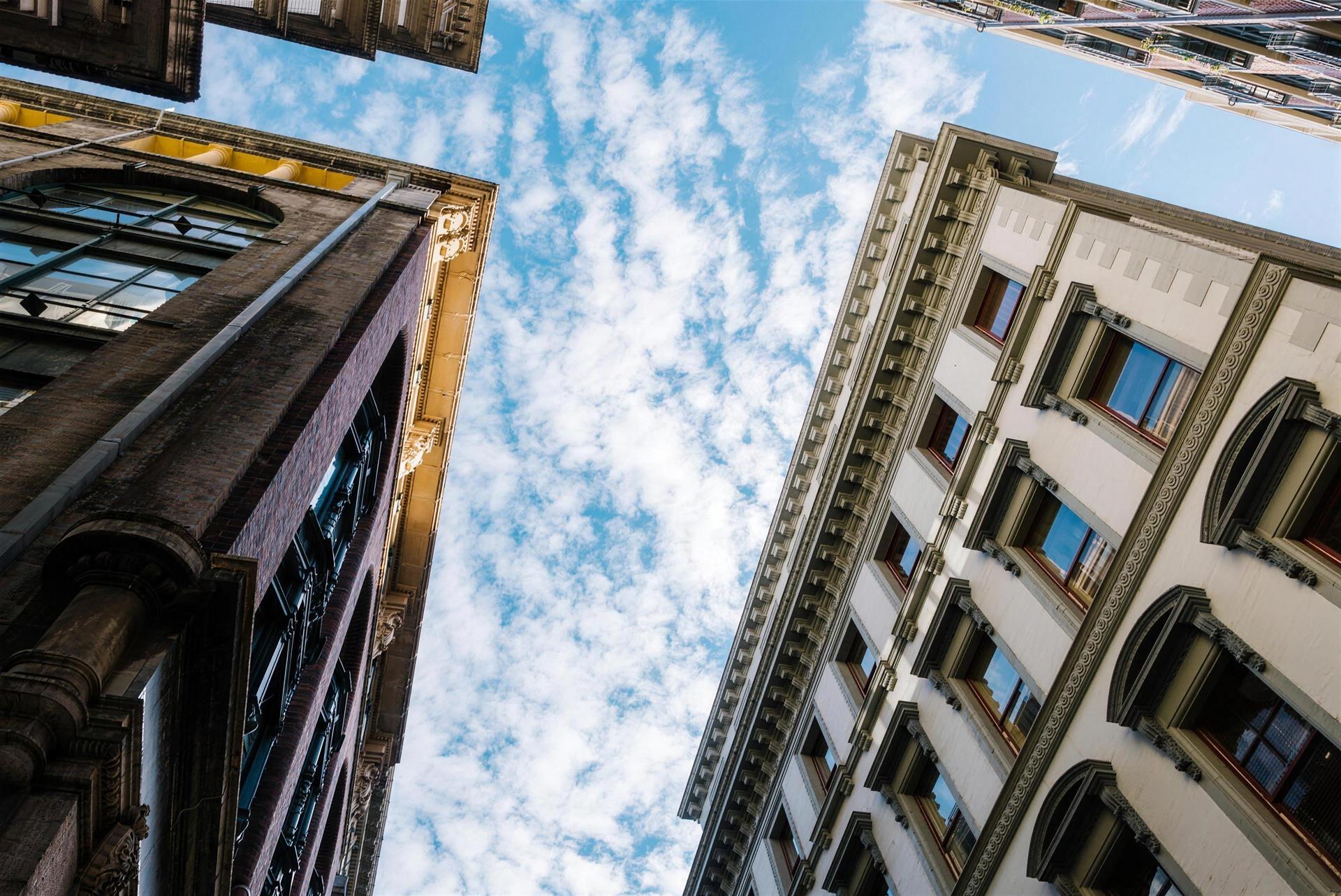 Blick von unten zwischen zwei historischen Häuserfassaden in den blauen Himmel