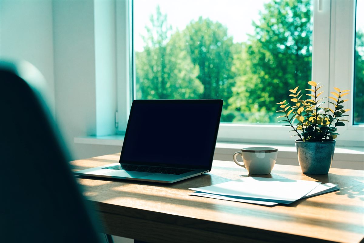 Heller Arbeitsplatz aus Eiche mit Laptop und Unterlagen am Fenster, Blick ins Grüne