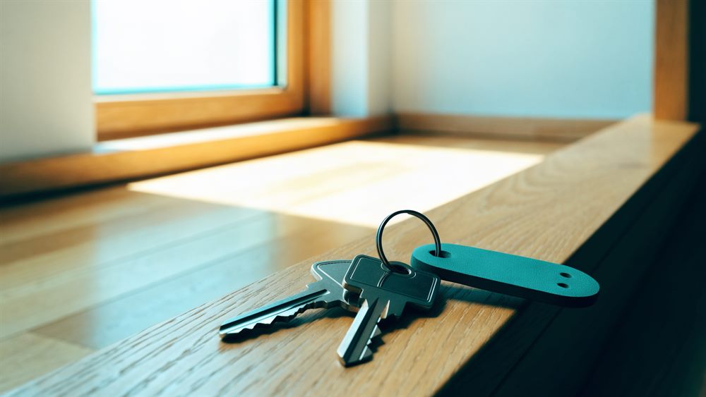 Wohnungsschlüssel mit Anhänger auf einer sonnigen Fensterbank aus Eiche