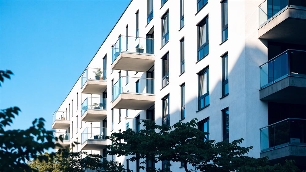 Moderner Wohnblock mit weißer Fassade und Balkonen vor blauem Himmel